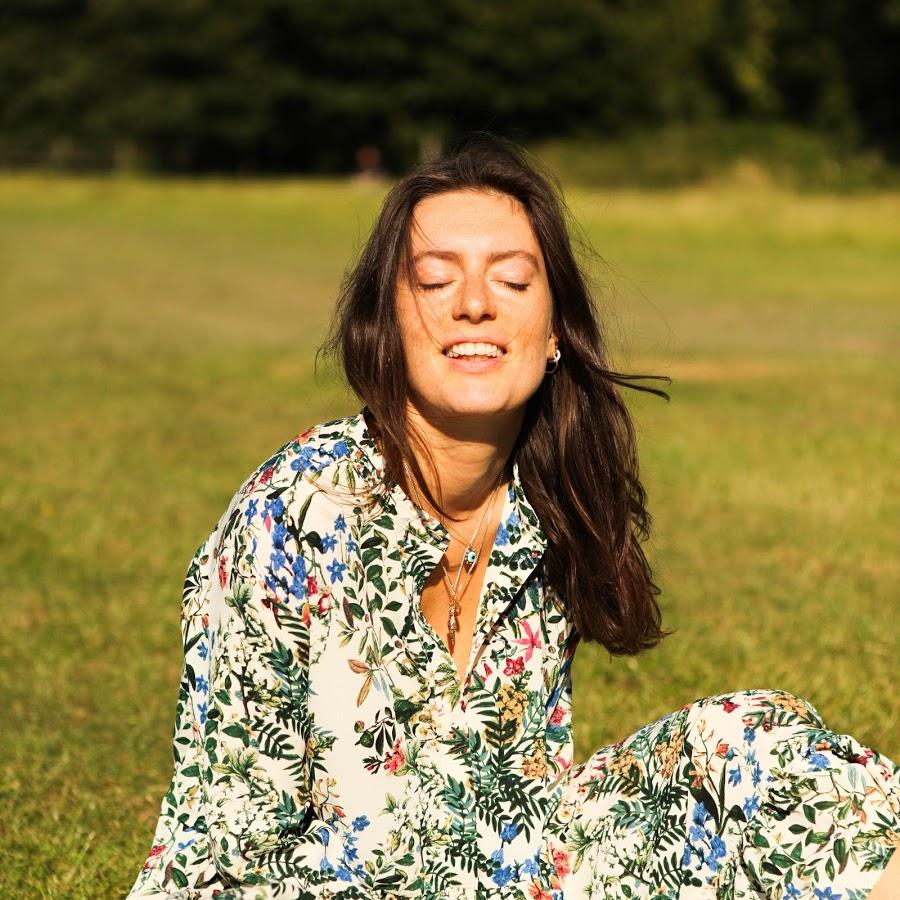Grace Kingswell Nutritional Therapist - female with long dark hair wearing a floral dress sits in a field wearing a floral dress