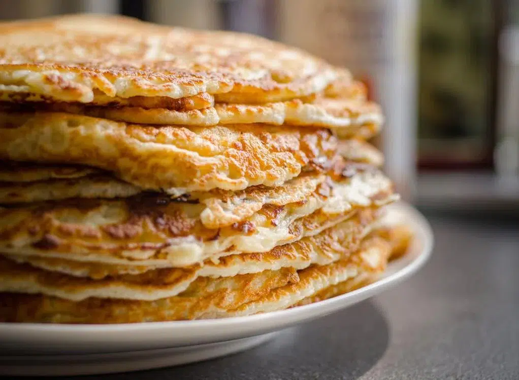A stack of golden gluten free banana pancakes on a white plate